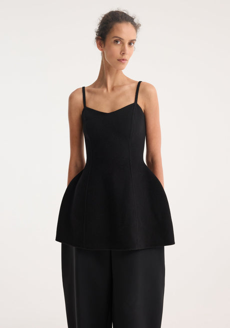 Model wearing Bustier double-faced top in black, featuring a fitted silhouette with thin straps and a flared peplum hem, paired with wide-leg trousers.