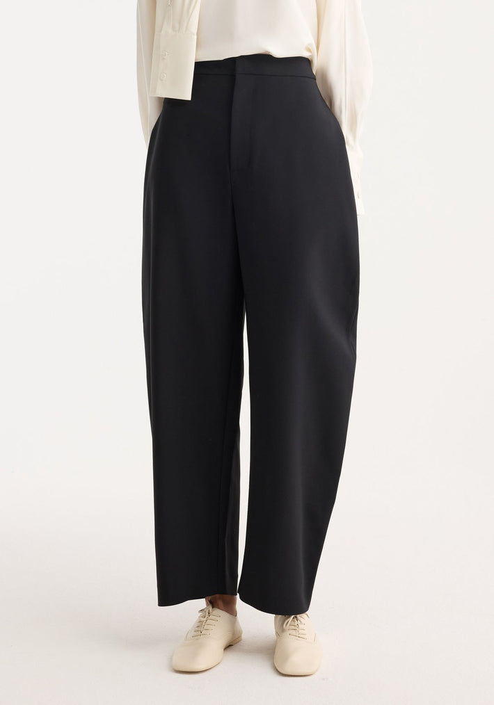 Sculptural trousers in black featuring a high waist and balloon leg, paired with lace-up cream shoes for a modern, statement-making silhouette.