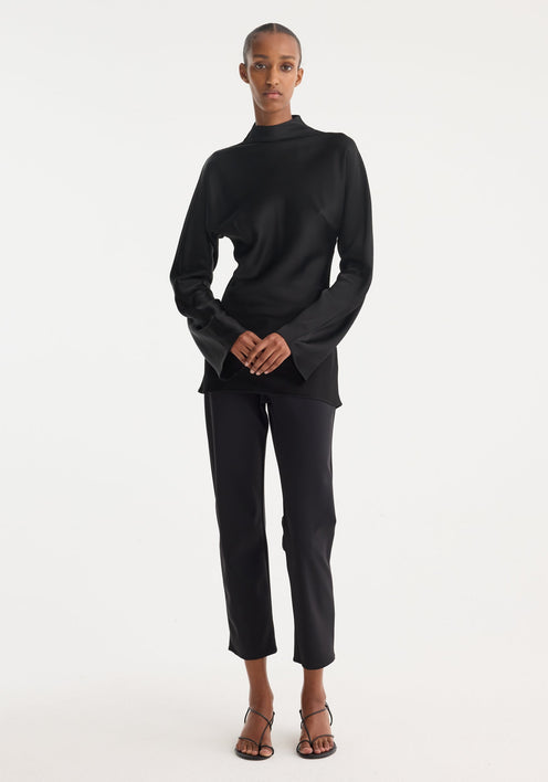 Model wearing a Satin waisted top | black, featuring a mock neck, long flared sleeves, and a slim-fit design with a seamless back zip closure.