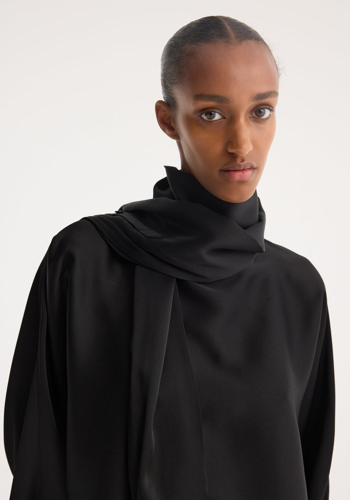 Woman wearing Foulard satin top with high neck, draped foulard-style sleeves creating a scarf effect, showcasing a fluid silhouette.