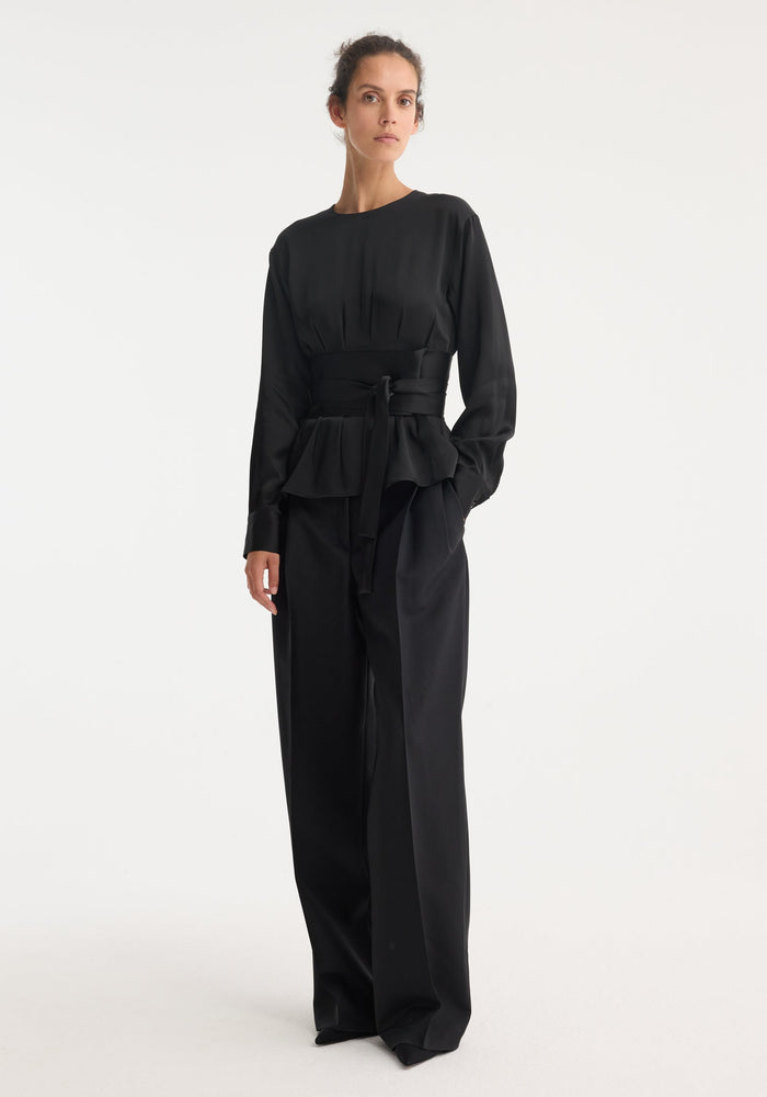 Kimono satin top | black on model, featuring long sleeves, round neckline, peplum waist, and wide sash, paired with high-waisted, wide-leg trousers.