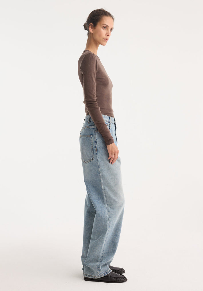 Woman wearing Fine merino long sleeve | brown melange with high-waisted jeans, showcasing a fitted silhouette and crew neck in a side-profile view.
