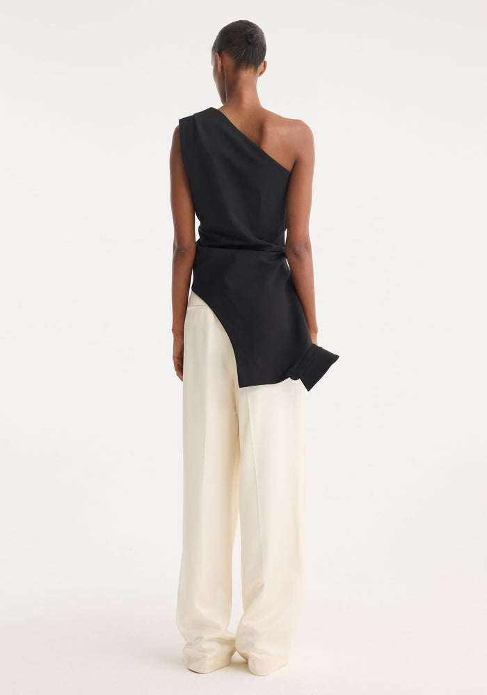 Model wearing Reimagined one shoulder top with asymmetrical, deconstructed design, featuring an upside down shirt collar, paired with high-waisted, wide-leg trousers.