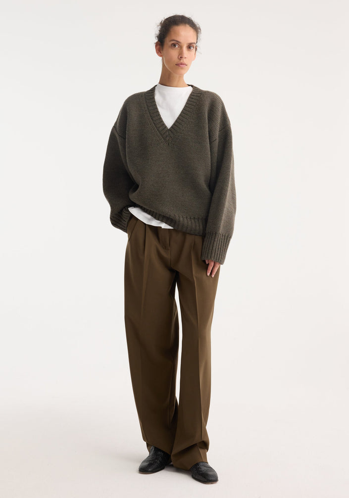 Sculptural compact v-neck | forest melange knit pullover sweater features a deep V-neck, dropped shoulders, ribbed cuffs, and hem, made from 100% wool by RÖHE.