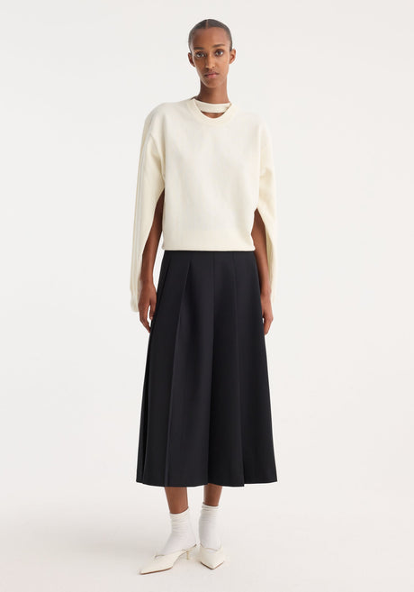 Model in minimalist attire showcasing a Crewneck with open neck | off white, featuring draped sleeves and a key-hole detail, paired with a black midi skirt.