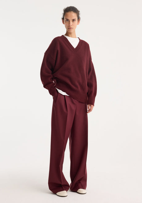 Mid-waist tailored trousers in burgundy, featuring a straight-leg cut with belt loops, a concealed front closure, and subtle pleats, made from 100% virgin wool.