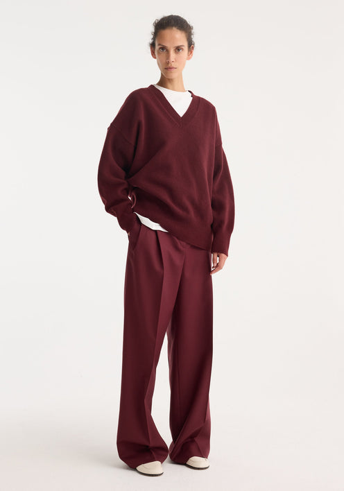 Mid-waist tailored trousers in burgundy, featuring a straight-leg cut with belt loops, a concealed front closure, and subtle pleats, made from 100% virgin wool.