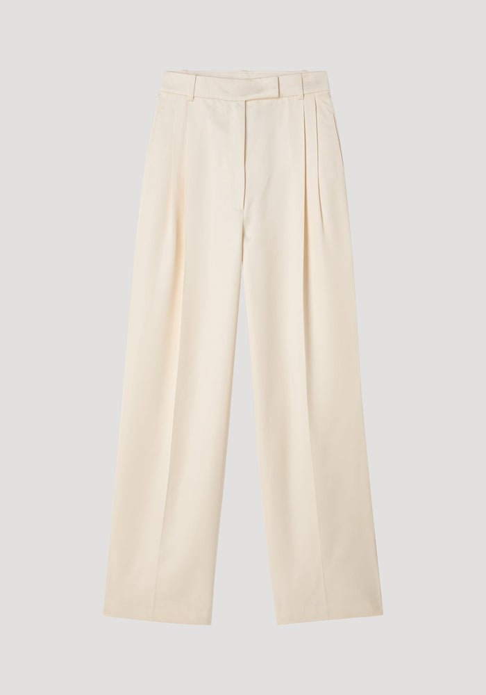 High-waist satin trousers in cream with a tailored waistband, front and back pleats, and welt pockets, laid flat on a neutral background.