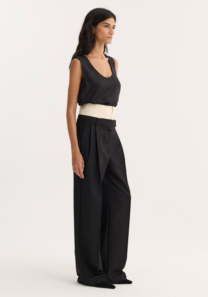 Corset trousers | black: Model in profile wearing high-waisted, wide-leg trousers with a structured off-white corset belt, paired with a sleek black scoop-neck top.