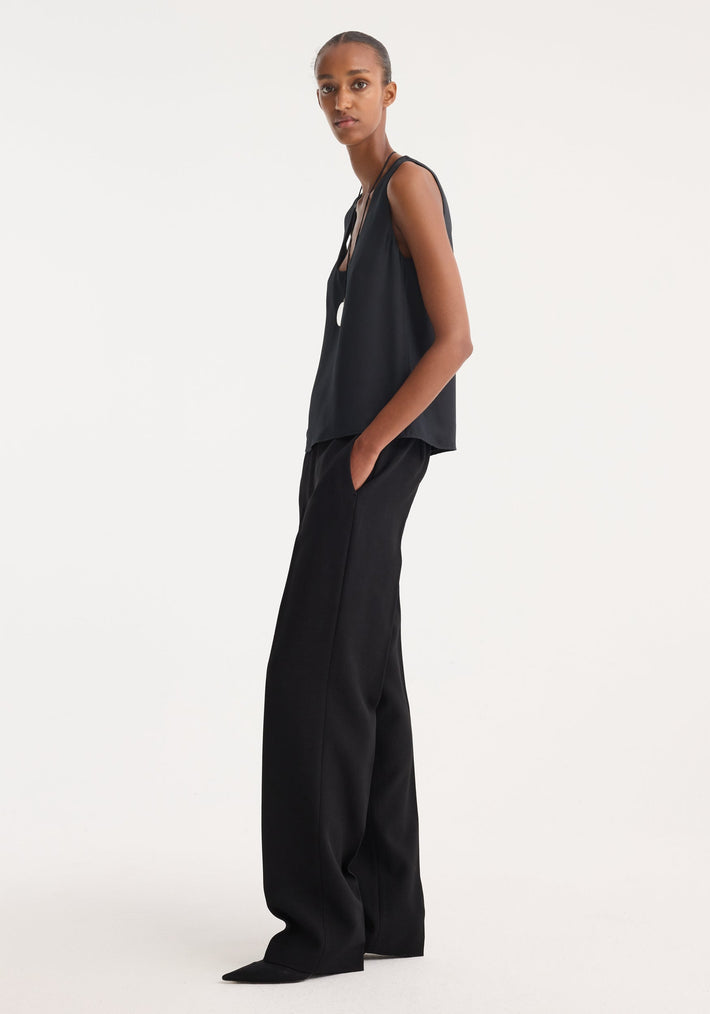 Model in high-waisted Straight leg trousers | black with sharp front pleat, tailored waistband, and side pockets, showcasing an elegant, refined silhouette.