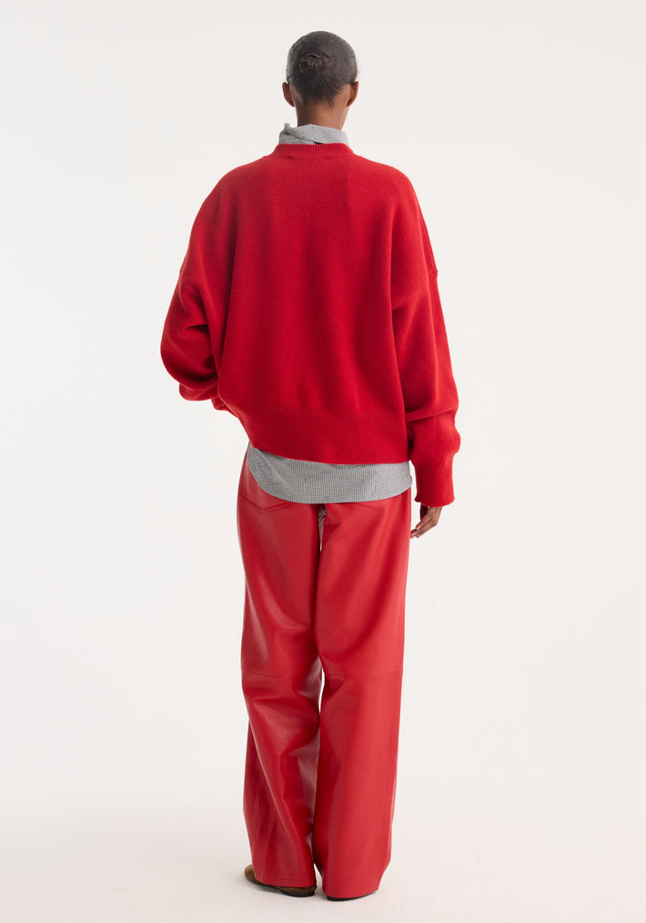 Baggy leather trousers | rosso showcased from behind, highlighting high-waisted, wide-leg design in soft nappa lamb leather. Modeled with a red sweater and checkered shirt.