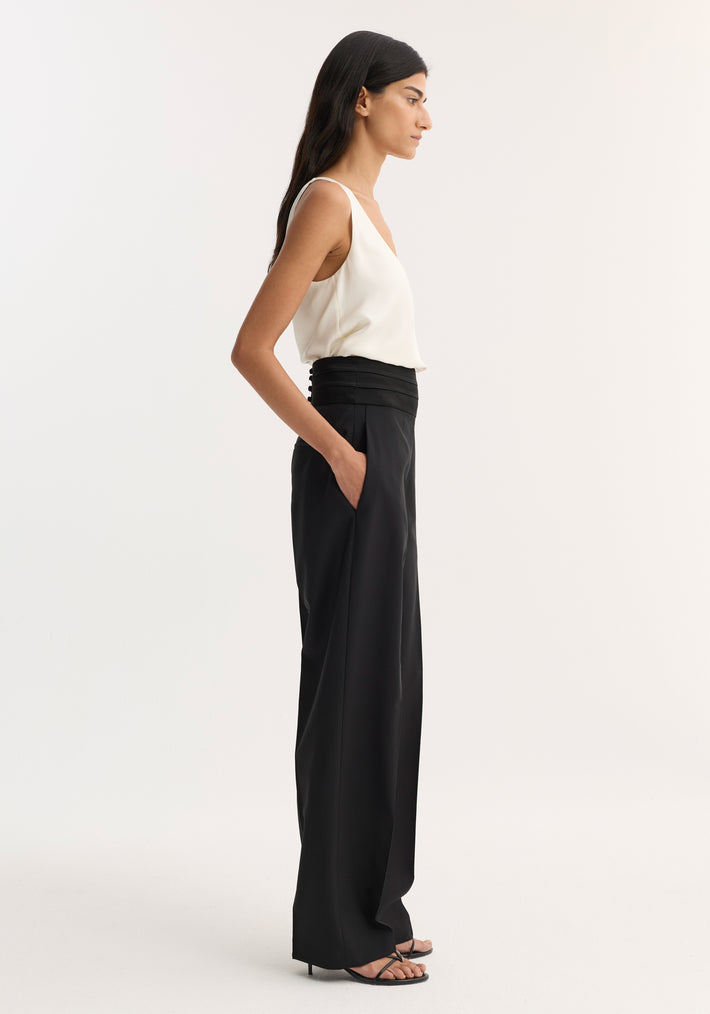 Model wearing Satin Cumberband Trousers in black, featuring a structured waistband and side pockets, paired with a cream V-neck camisole.