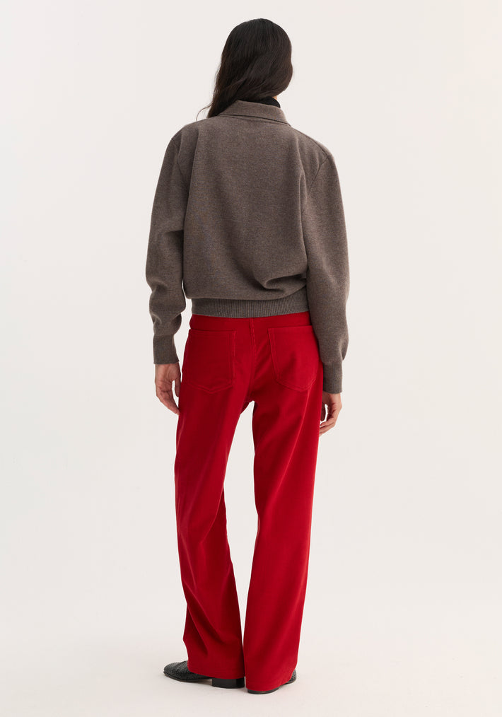Back view of model wearing Relaxed corduroy trousers | rosso in vibrant red with back patch pockets, paired with a muted sweater and low-profile shoes.