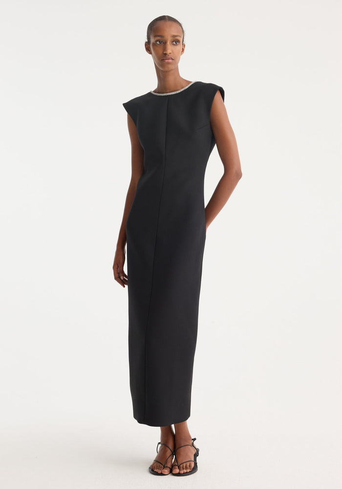 Open back appliqué dress | black: A woman in a form-fitting, sleeveless black maxi dress with a rhinestone neckline, open back, and caped shoulders, paired with black sandals.