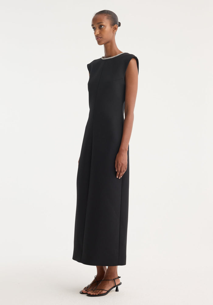 Model in Open Back Appliqué Dress | Black, featuring caped sleeves, crystal trim neckline, and open back, paired with low-heel sandals.