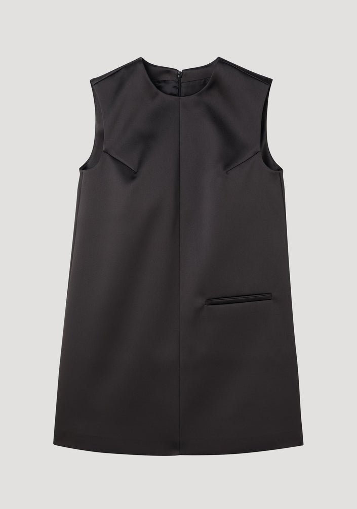Sculptural cape dress in black, sleeveless A-line with a high neckline, single welt pocket, center-front seam, and dramatic box pleats for a tailored fit.