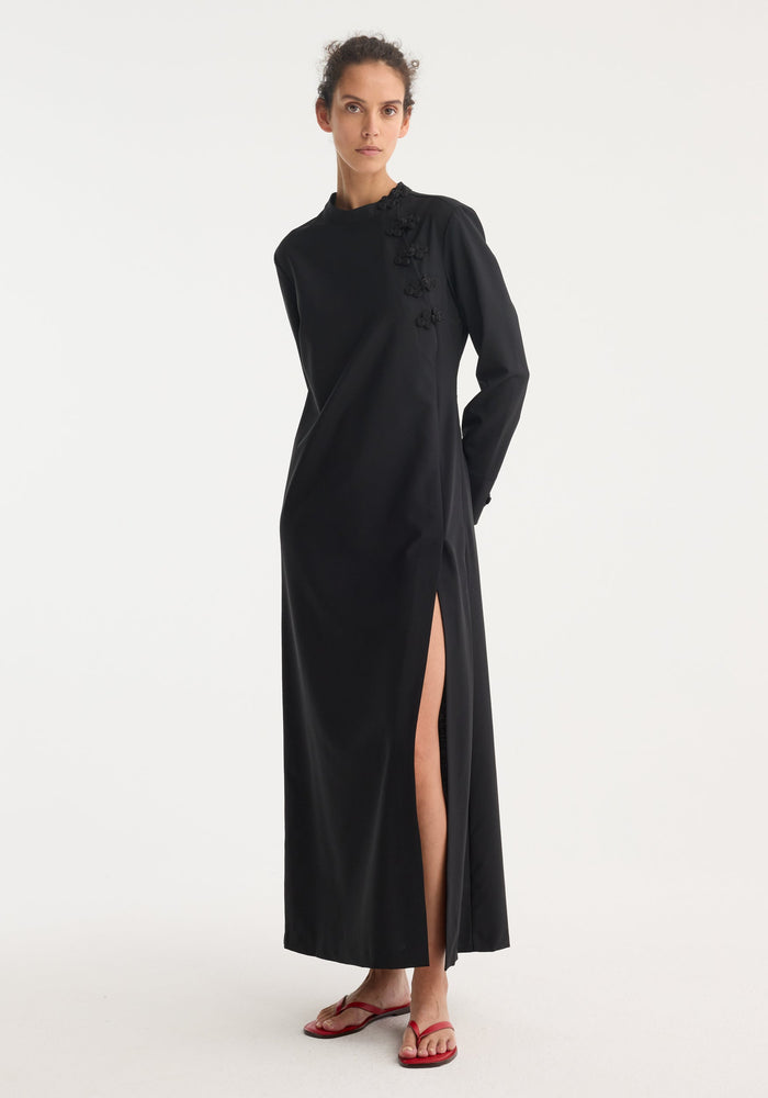 Model wearing Mandarin dress | black, featuring long sleeves, asymmetrical pankou closures on shoulder, high side slit, crafted in virgin wool and mohair blend.