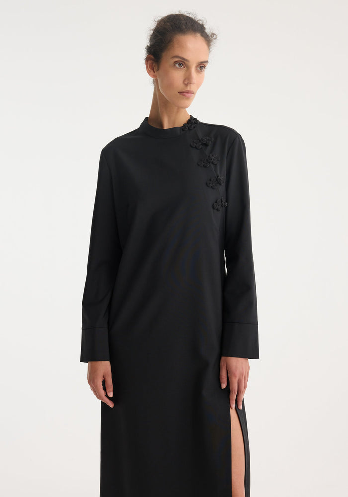 Model in a Mandarin dress | black, featuring long sleeves, floor-length design, asymmetrical pankou closures, high neckline, and thigh-high side slit.