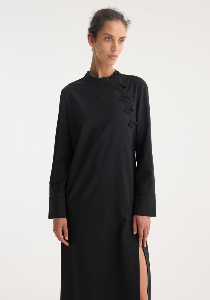 Model in a Mandarin dress | black, featuring long sleeves, floor-length design, asymmetrical pankou closures, high neckline, and thigh-high side slit.