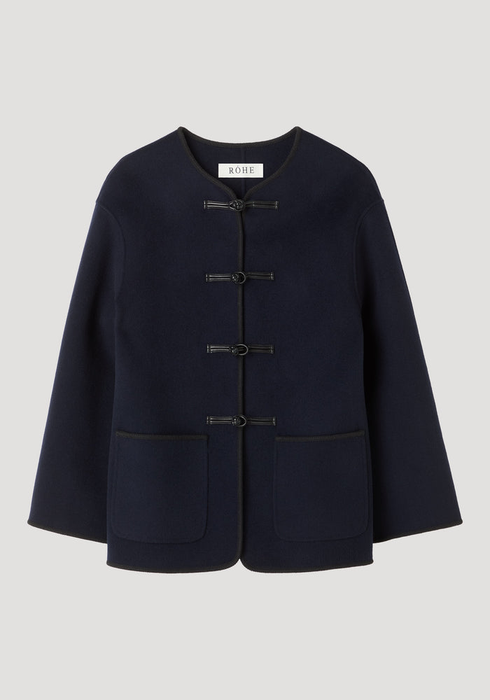 Double-faced wool pankou jacket in navy with frog-style toggles, embroidered edges, and patch pockets, showcasing traditional Chinese craftsmanship and a modern silhouette.