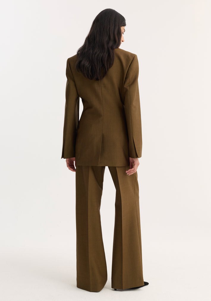 Woman in an olive-brown suit, showcasing the Hourglass blazer with a cinched waist, sharp notch lapel, and matching wide-leg trousers, viewed from the back.