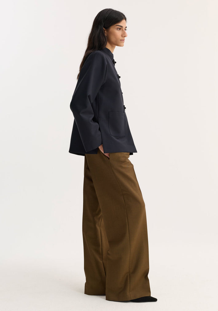 Pankou closure jacket in navy with mandarin collar and patch pockets, paired with wide-leg trousers, showcased in a minimalist studio fashion shot.