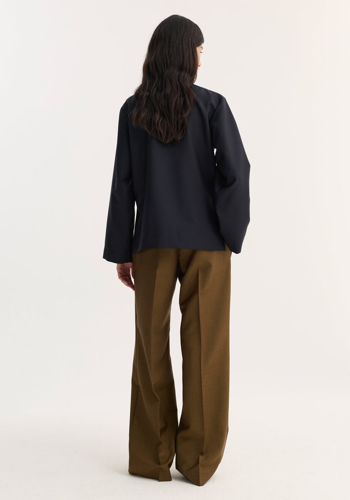 Back view of a person wearing a Pankou closure jacket in navy with long sleeves and high-waisted, wide-leg trousers in olive-brown.