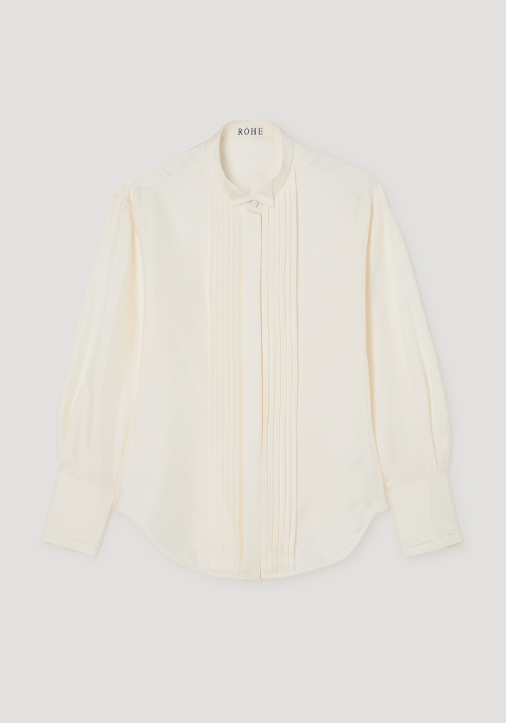 Shaped tuxedo silk shirt | cream featuring a stand-up collar, vertical pintucks, and high cuffs. Crafted from 100% silk, offering a waisted fit and curved hemline.