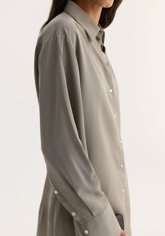 Side profile of a person wearing a Relaxed shaped shirt | light grey stripe, featuring fine pin-stripes, elongated sleeve plackets, and mother-of-pearl buttons.