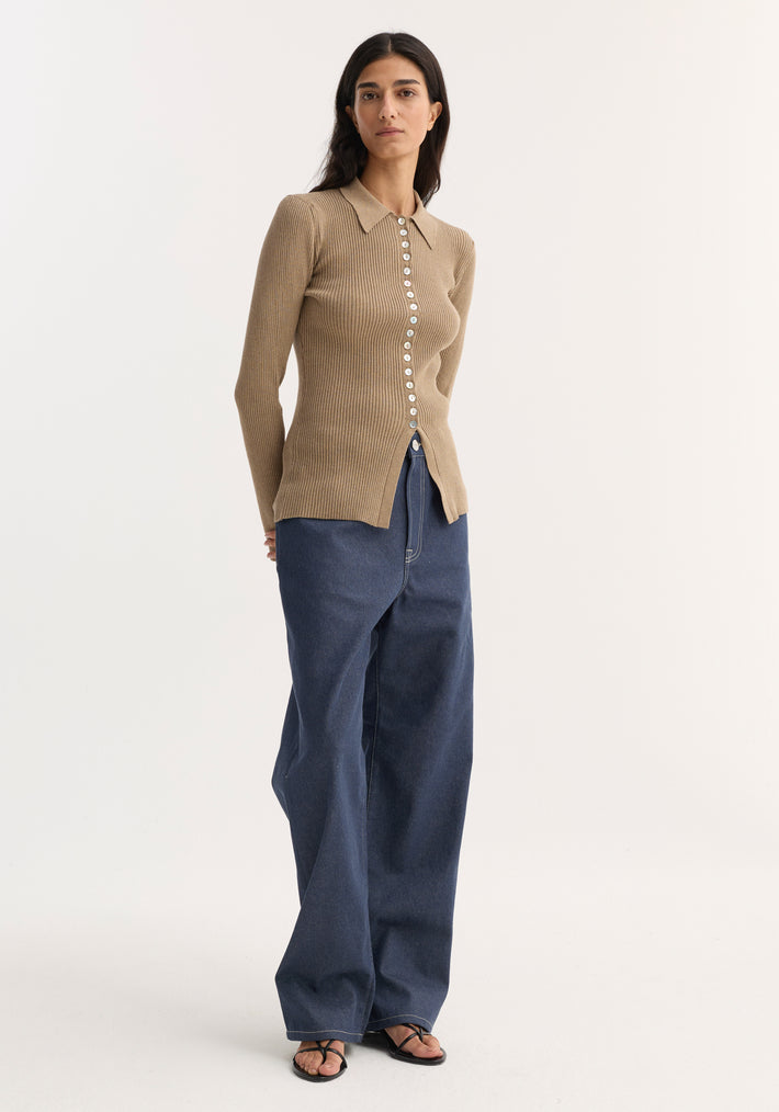 Model wearing Elongated rib cardigan | taupe melange, featuring a fitted silhouette, pointed collar, front buttons, and slightly flared hem, paired with dark blue wide-leg jeans.