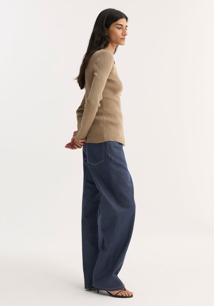 Woman in profile wearing Elongated rib cardigan in taupe melange, fitted with button closures and collar, paired with wide-leg jeans and strappy sandals.