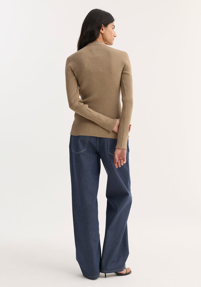 Woman wearing Elongated rib cardigan in taupe melange, showcasing a fitted silhouette with button closures and collar, paired with wide-leg jeans and heeled sandals.