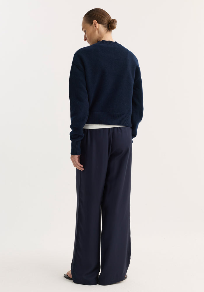 Person wearing a Short boiled cardigan | navy, showcasing the cropped button-up design, high crew neck, and drop shoulders with a soft, structured texture.