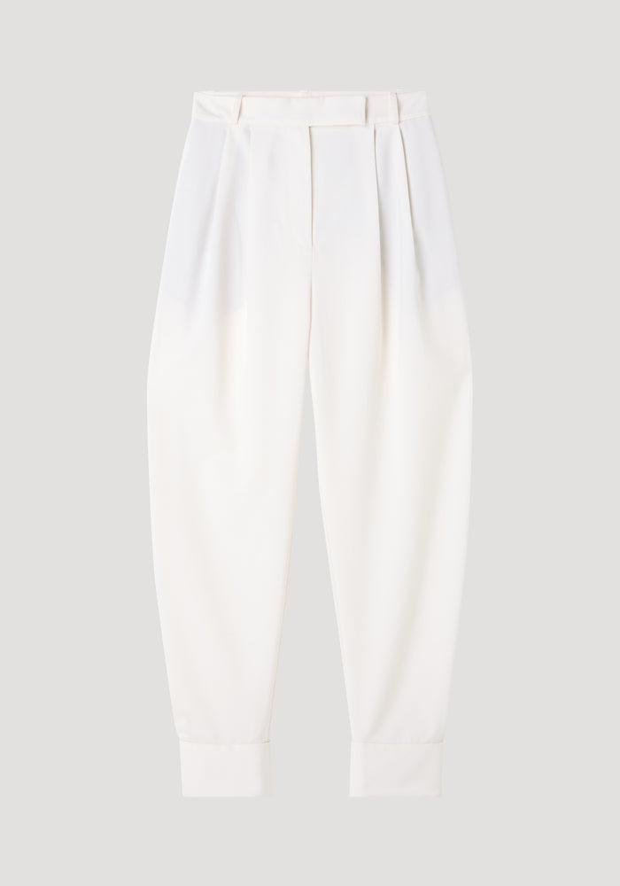 Barrel leg trousers in off white, featuring high-waisted design, front pleats, tapered legs, belt loops, and ankle cuffs, crafted from a soft wool blend.