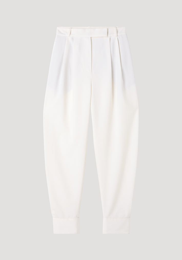 Barrel leg trousers in off white, featuring high-waisted design, front pleats, tapered legs, belt loops, and ankle cuffs, crafted from a soft wool blend.