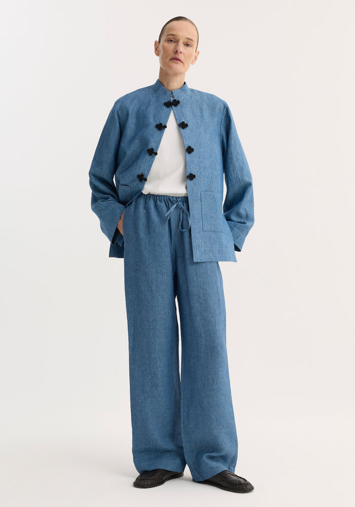 Person wearing Relaxed fit trousers | ocean blue, featuring a wide leg and drawstring waist, styled with a matching jacket and moccasin-style shoes.