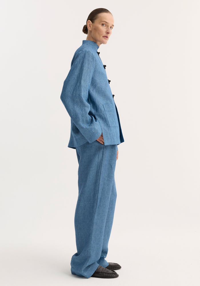 Model in profile wearing Relaxed fit trousers in ocean blue, featuring a long, wide leg, and drawstring waistband, styled with a matching jacket.