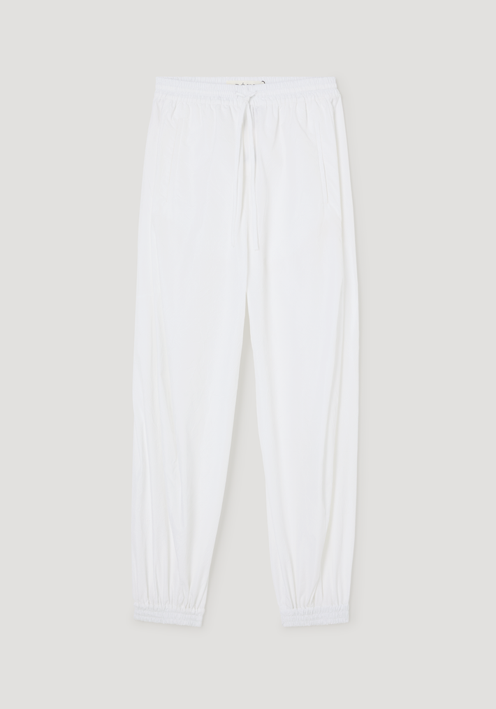 Balloon track pants in optic white with crinkled texture, featuring an elastic waistband, drawstring, welt pockets, and elastic cuffs for a voluminous look.