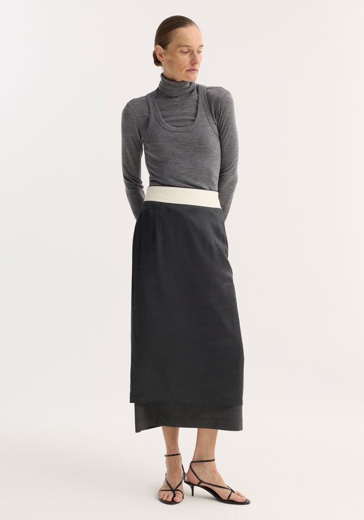 Model in fitted Double-layer wool top, mid grey melange, featuring a turtleneck and tank combo, paired with a high-waisted black skirt and sandals.