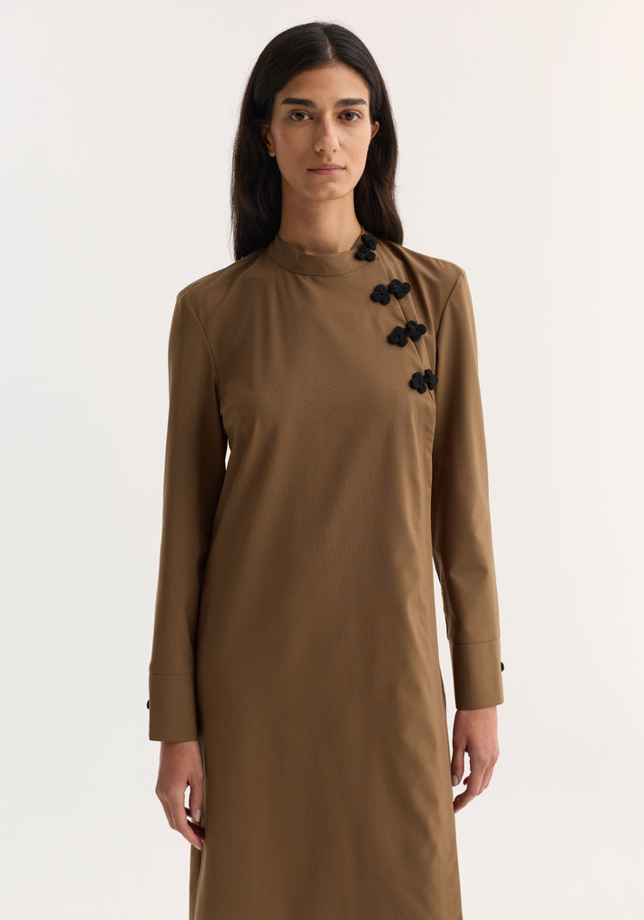 Model wearing Pankou closure dress | mocha, featuring long sleeves, high neck, decorative frog closures, tailored fit, and minimalist style against a plain background.
