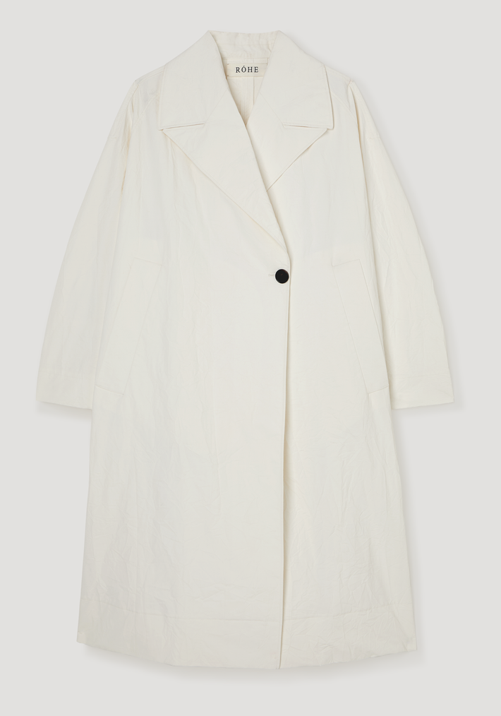 Oversized crushed cotton coat in off-white with a notched lapel, three-quarter raglan sleeves, single black button, and diagonal slit pockets.