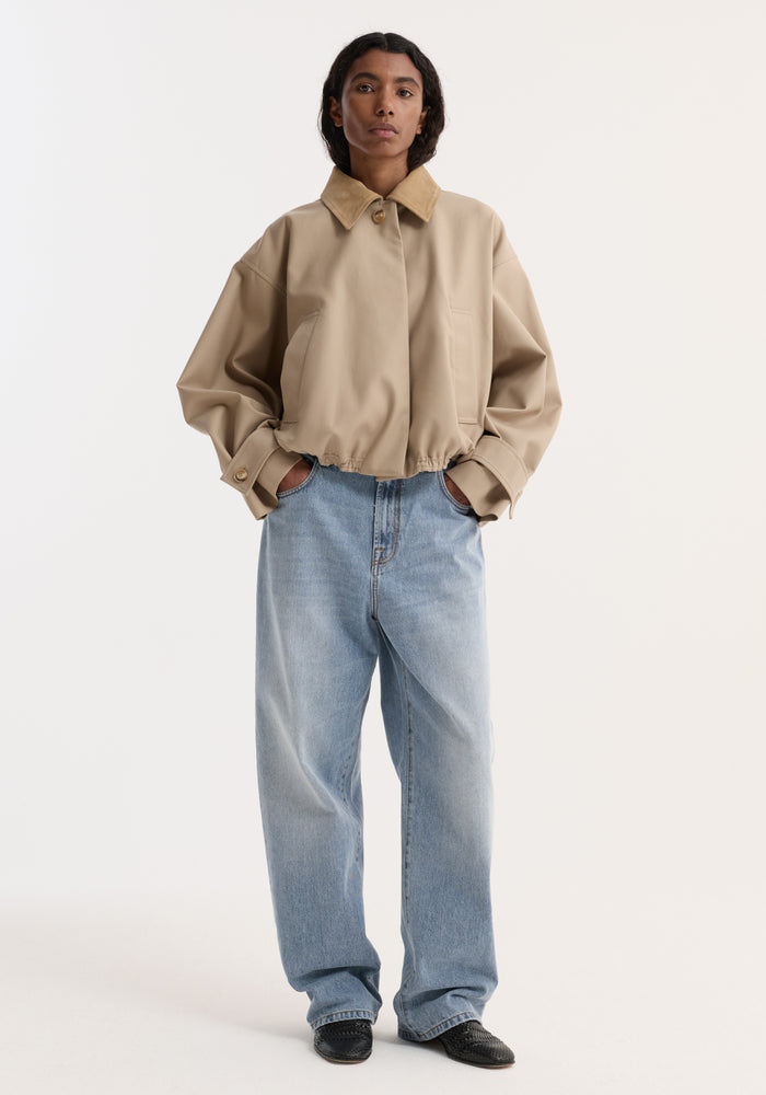 Model wearing Suede Collar Blouson Jacket | Sand, showcasing a cropped, loose fit with wide sleeves, suede collar, and dropped shoulders, paired with light denim jeans.