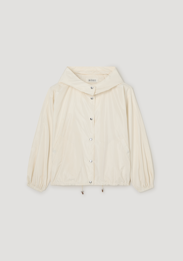 Volume silk-blend jacket in cream, featuring a hood, snap-button front, elastic cuffs, slanted pockets, and a drawstring hem with wooden toggles.