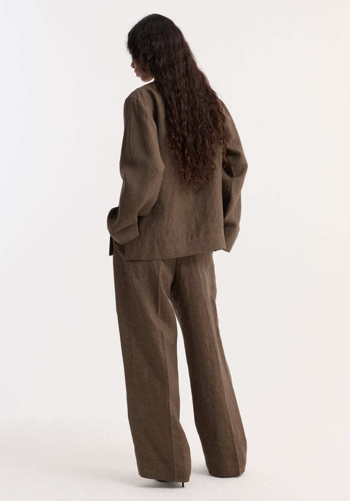 Person with long hair wears a Pankou closure linen jacket in brown melange, showing back view with hands in pockets against a plain background.