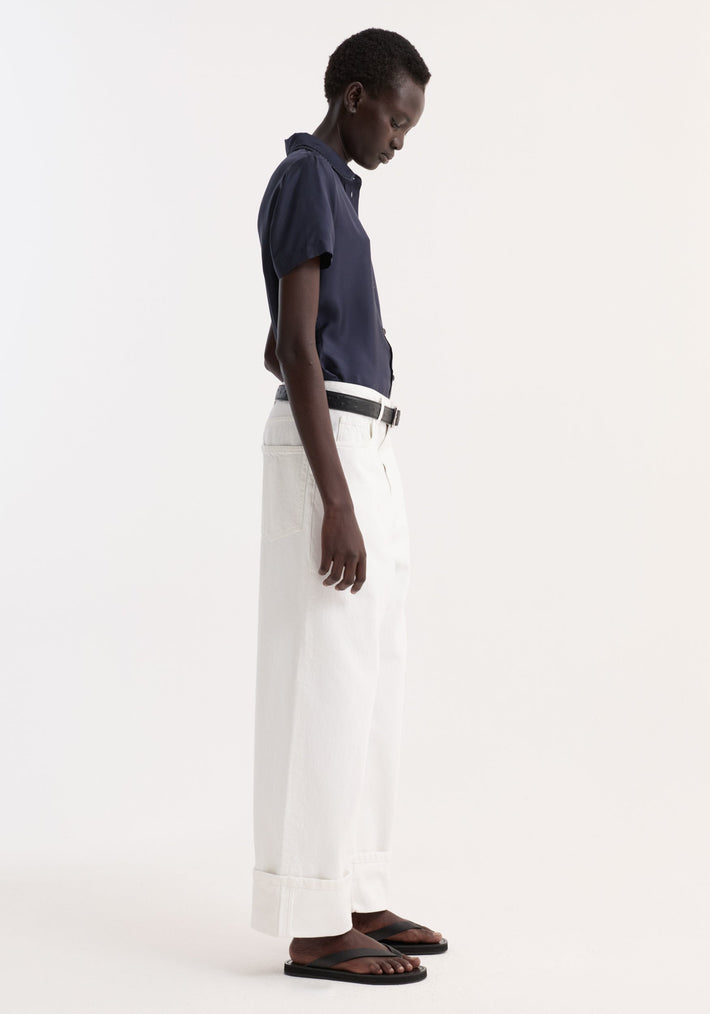 Model wearing Embroidered silk fitted shirt | night with short sleeves and delicate embroidery, paired with white wide-leg trousers and black sandals.