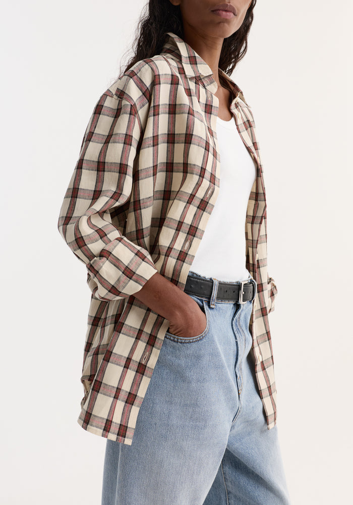 Person wearing an Oversized check shirt | red table check over a white tank top, paired with light-wash jeans. Shirt is unbuttoned, sleeves rolled up.
