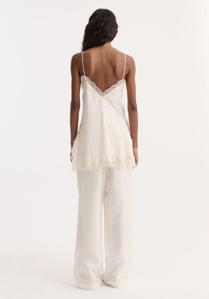 Lace camisole in off white, featuring a V-shaped back with lace trim, adjustable straps, and paired with matching wide-leg trousers, creating an elegant silhouette.