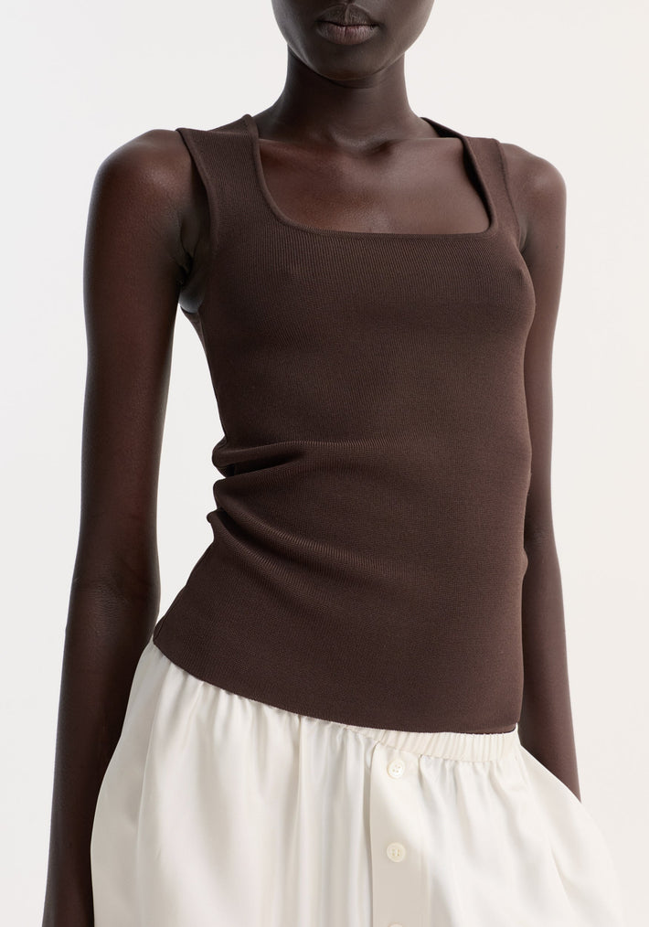 Bustier shaped knitted top in dark chocolate with a fitted silhouette and square neckline, paired with a high-waisted white skirt featuring button details.