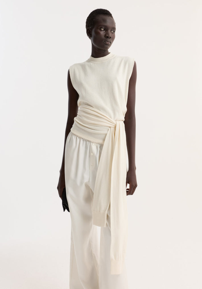 Model wearing Open back knitted wrap top | off white, featuring an open back, sash-style sleeves, and a tied waist, paired with wide-leg trousers.