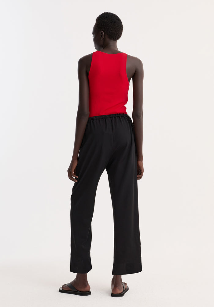 Cropped wide leg trousers in black, featuring an ankle-length fit with elasticated waist and side pockets, worn by a model to showcase their relaxed drape.